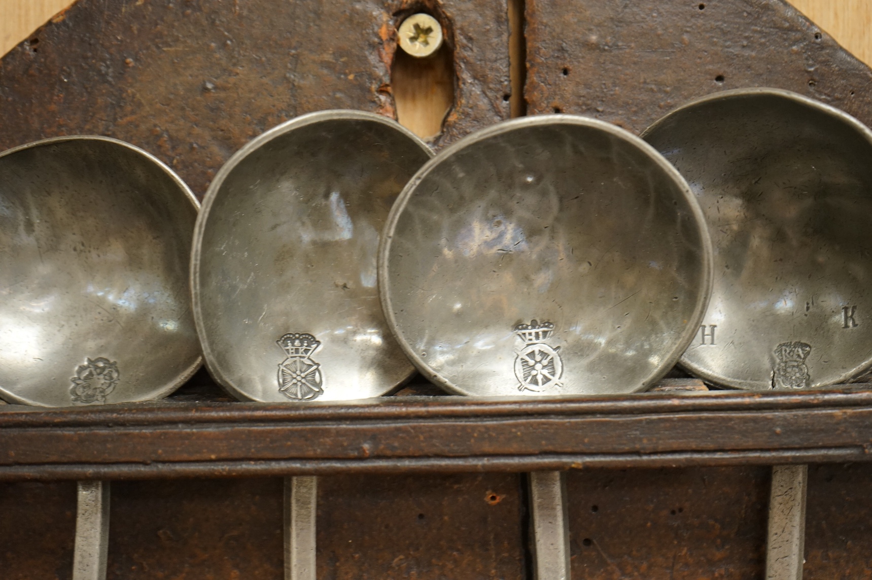 An 18th century oak spoon rack and collection of pewter spoons, 55cm high. Condition - wood cracked